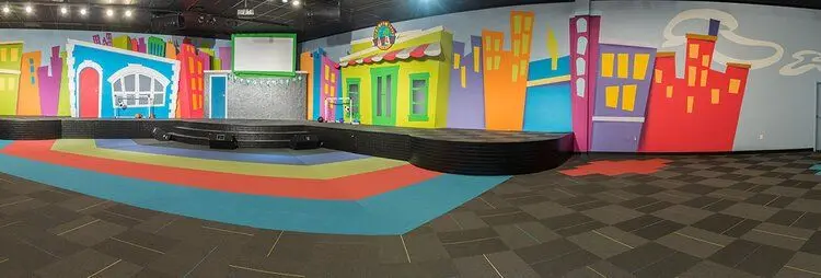 Children's play area with a bright city mural and colored flooring
