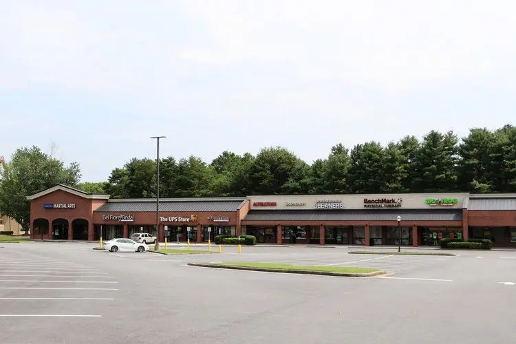 Long brick retail center with a parking lot in front